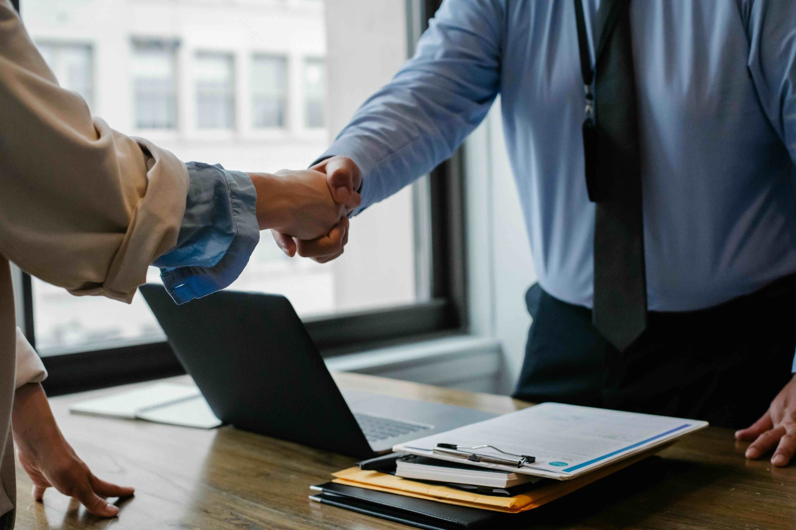 Shaking Hands Two people inside of an office shaking hands over a desk.